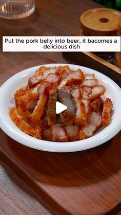 a white plate topped with sliced meat on top of a wooden table