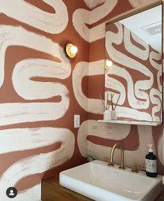 a bathroom sink sitting under a mirror in front of a wall painted with white paint