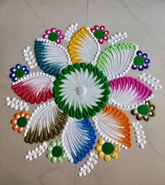 a colorful flower design on the floor with white and green flowers in the center, surrounded by multicolored beads