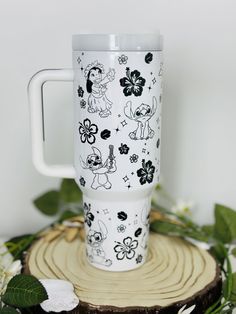 a white cup with black and white designs on it sitting on top of a tree stump