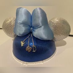 The Disneyland 60th Anniversary Minnie Mouse Ear Hat From 2015! This Beautiful Ear Hat Is Covered In Blue And Silver Sequins With A Light Blue Satin Bow On Top. It Features Three Charms That Hang Down From The Bow - A Castle, The Disneyland Logo, And The Number 60. It Has An Elastic Chin Strap To Make Sure It Stays On Securely! Disneyland Logo, Ear Hat, Minnie Mouse Ears, Ear Hats, 60th Anniversary, A Castle, Disney Accessories, Satin Bow, Mouse Ears