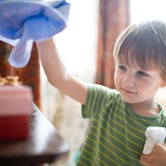 a young boy holding a cleaning cloth and a spray bottle