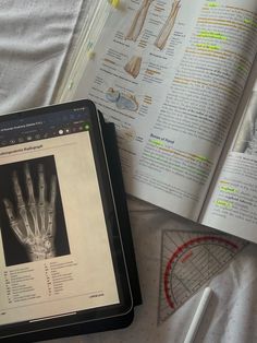 an open book with skeleton images on it next to a tablet computer and other medical equipment