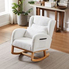 a white rocking chair sitting on top of a hard wood floor next to a potted plant