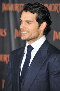 a man in a suit and tie smiling for the camera