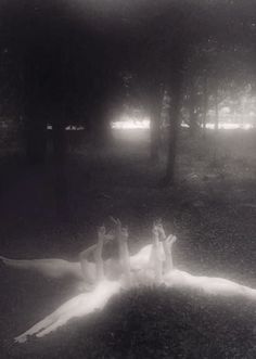 two women laying on the ground in front of some trees with their legs spread out