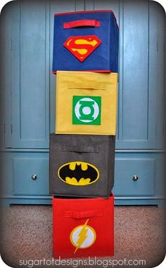 a stack of cardboard boxes with batman and superman logos on them, sitting in front of a blue wall