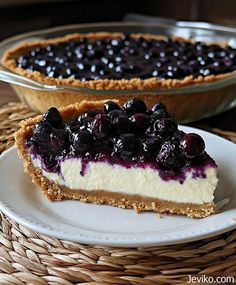 a slice of cheesecake with blueberries is on a plate next to the pie