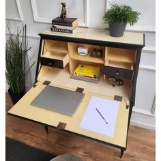 an open laptop computer sitting on top of a desk next to a potted plant