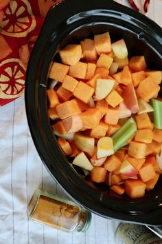 chopped up vegetables in a crock pot next to some salt and pepper shakers