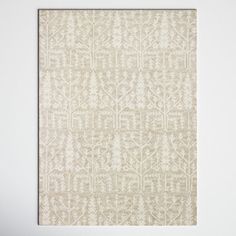 a white and beige area rug with an intricate design on the bottom, in front of a white wall