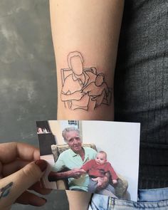 a person holding up a small photo with a drawing on the side of their arm