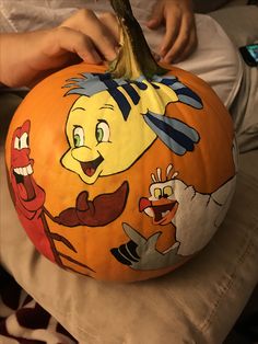 a person is painting a pumpkin with cartoon characters on it