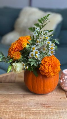 a vase filled with flowers sitting on top of a wooden table next to a couch