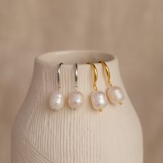 Fall in love with the timeless beauty of our Dangling Pearl Drop Earrings. With their graceful design and lustrous pearls, these earrings capture the essence of romance and are perfect for completing your summer wedding look or embracing a minimalist boho style. Material: High Quality Solid 925 Sterling Silver Finish: Sterling Silver ∙ 18K Gold Featuring ~16.5mm Hook Earrings with ~10 x 8.5mm Dangling Pearl Charm Sold as a pair Model showcases a summery, romantic look featuring Vera Pave Huggies Silver Hoop Earrings With Pearl Charm For Wedding, Silver Feminine Earrings With Pearl Charm, Feminine Pearl Earrings In Silver, Feminine Silver Earrings With Pearl Charm, Feminine Silver Pearl Earrings, Dainty Pearl Charm Drop Earrings, Minimalist Pearl Drop Bridal Earrings, Elegant Everyday Pearl Pendant Earrings, Delicate Pearl Charm Earrings For Everyday