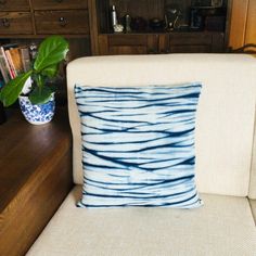 a blue and white pillow sitting on top of a chair next to a book shelf