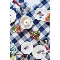 a table topped with plates and cups filled with desserts on top of a blue checkered table cloth