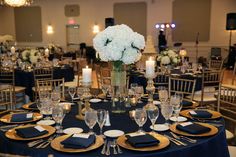 the table is set with gold and black plates, silverware, and white flowers