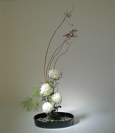 a vase filled with white flowers sitting on top of a black table next to a wall