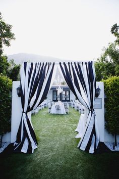 an outdoor wedding setup with black and white drapes, chairs and tablecloths