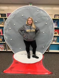 a woman standing in front of a fake snow globe