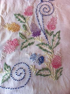 a close up of a piece of cloth with flowers and swirls embroidered on it