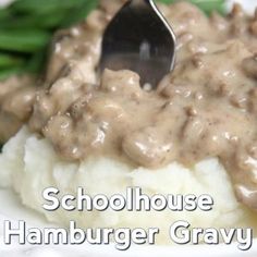 a white plate topped with mashed potatoes covered in gravy and a spoon