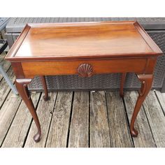 an old wooden table with a drawer on it