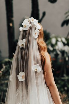 the back of a bride's veil with white flowers on her head and shoulders