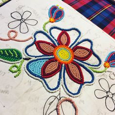 a table topped with lots of beaded designs on top of a white table cloth