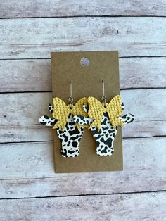 two cow shaped earrings with yellow bows on them