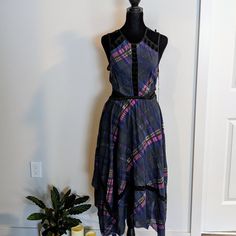 a dress on a mannequin next to a potted plant and candle holder