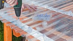 a person using a drill to attach the top of a table with clear plastic covering