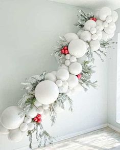 a christmas wreath made out of white balls and greenery hanging from the side of a wall