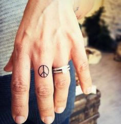 a person with a peace sign tattoo on their finger