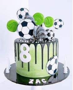 a birthday cake with soccer balls on top and the number eight is decorated in green icing