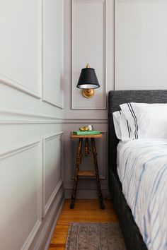 a bed sitting next to a night stand with a lamp on it's side