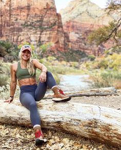 a woman sitting on top of a log next to a river