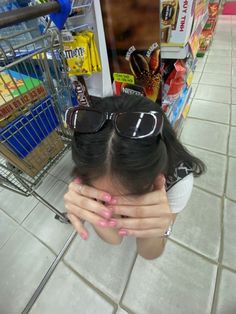 a woman with her hands on her face in front of a shopping cart