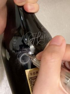 someone is writing on a bottle with a pen