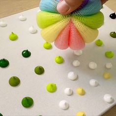 a person is holding a colorful object in front of some green and white balls on a table