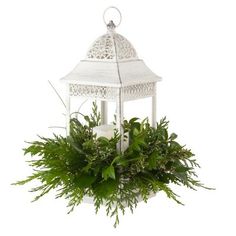 a white candle holder with greenery in it