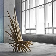 a chair made out of wooden sticks sitting in front of a large window with lots of windows