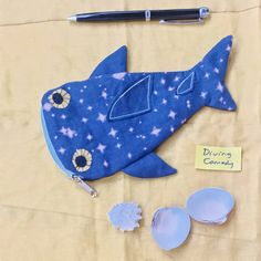 a blue shark purse next to other items on a sheet of paper with the words whale shark purse written below it