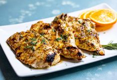 grilled chicken with herbs and orange slices on a plate