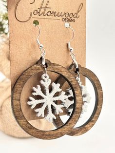 snowflake earrings are displayed in front of a cardboard box with the word cottonwood designs on it