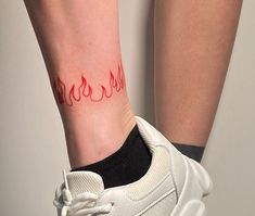 a woman's foot with a red tattoo on her left ankle and white sneakers