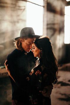 a man and woman standing next to each other in front of a window with sunlight streaming through the windows