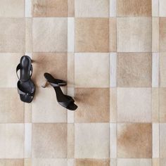 a pair of black high heeled shoes sitting on top of a tiled floor