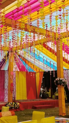 an outdoor event decorated with bright colored draping and yellow chairs under the canopy